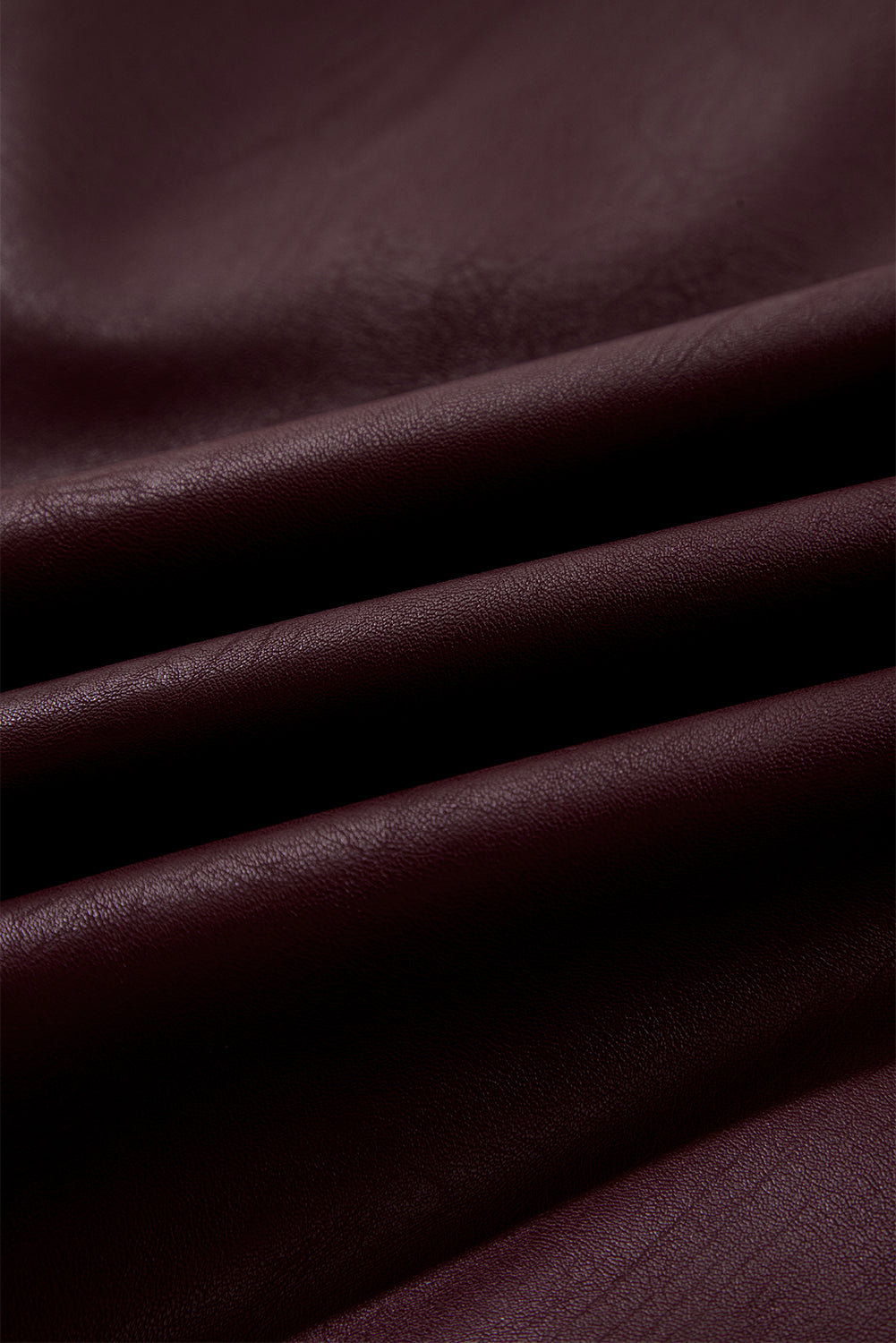 Close-up of folded dark burgundy leather fabric with smooth texture