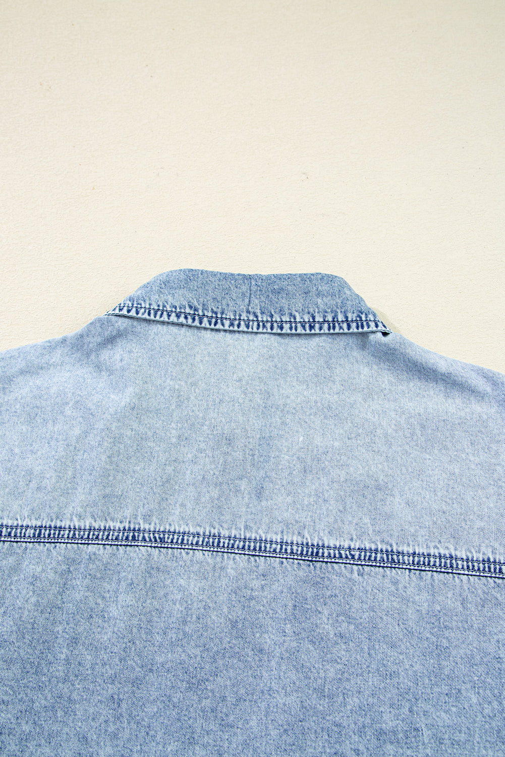 Close-up of light blue denim shirt collar and back yoke stitching