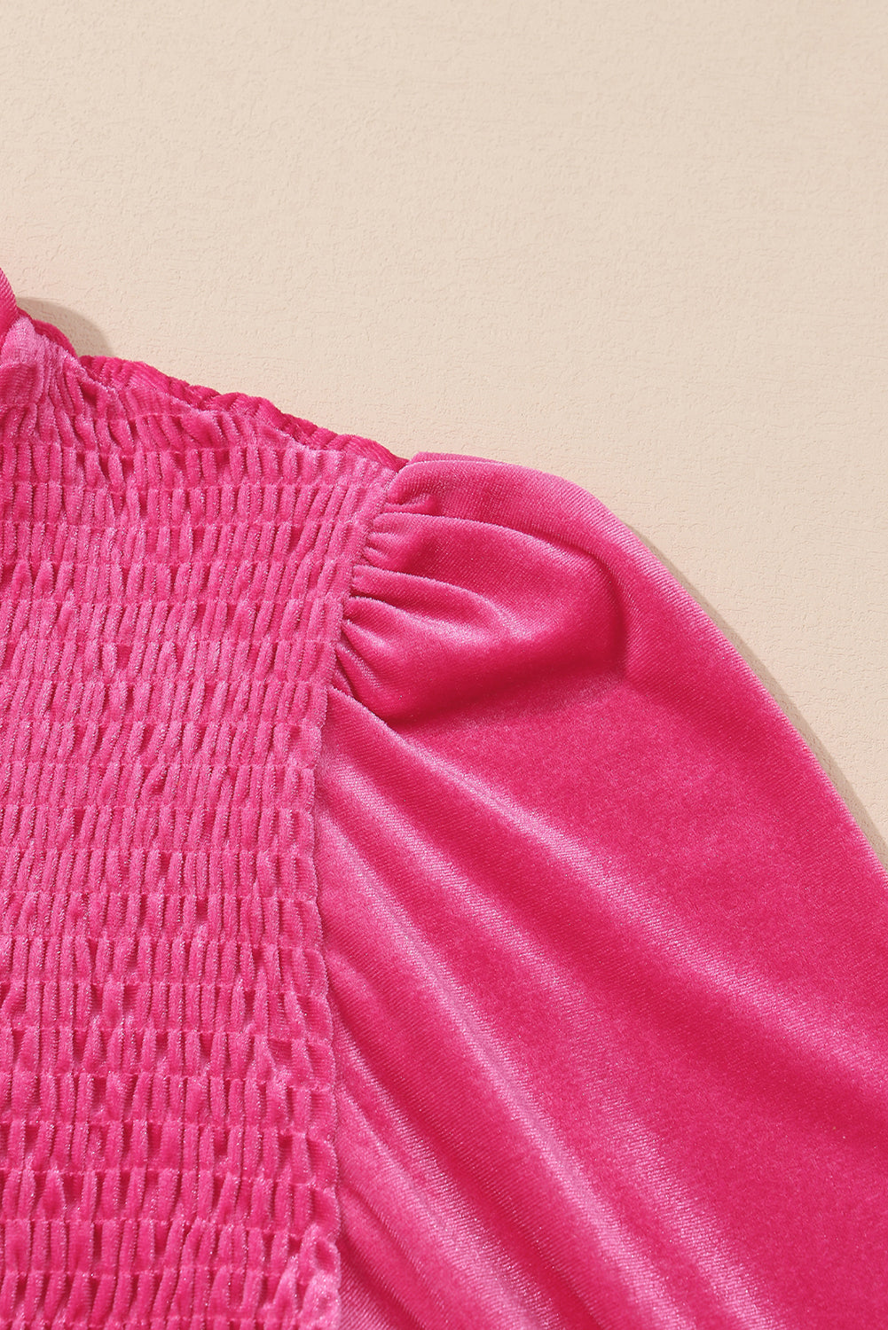 Close-up of bright pink velvet puff sleeve top with ruched bodice on neutral background
