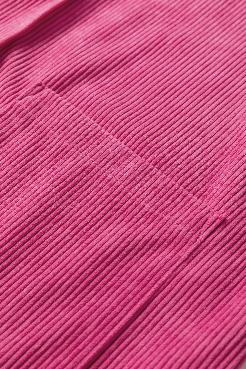 Close-up of pink ribbed corduroy fabric with visible seam detail