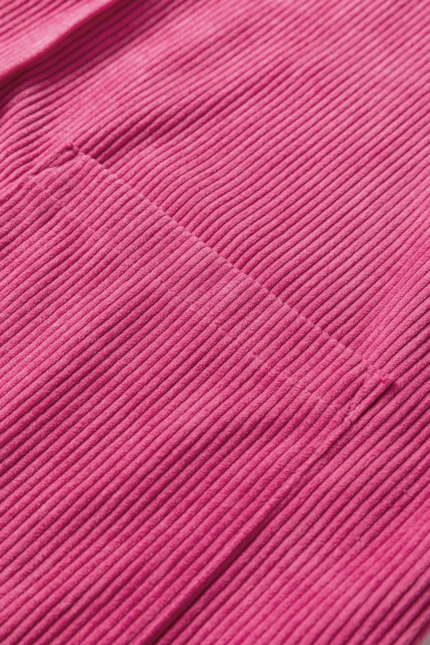 Close-up of pink ribbed corduroy fabric with visible seam detail
