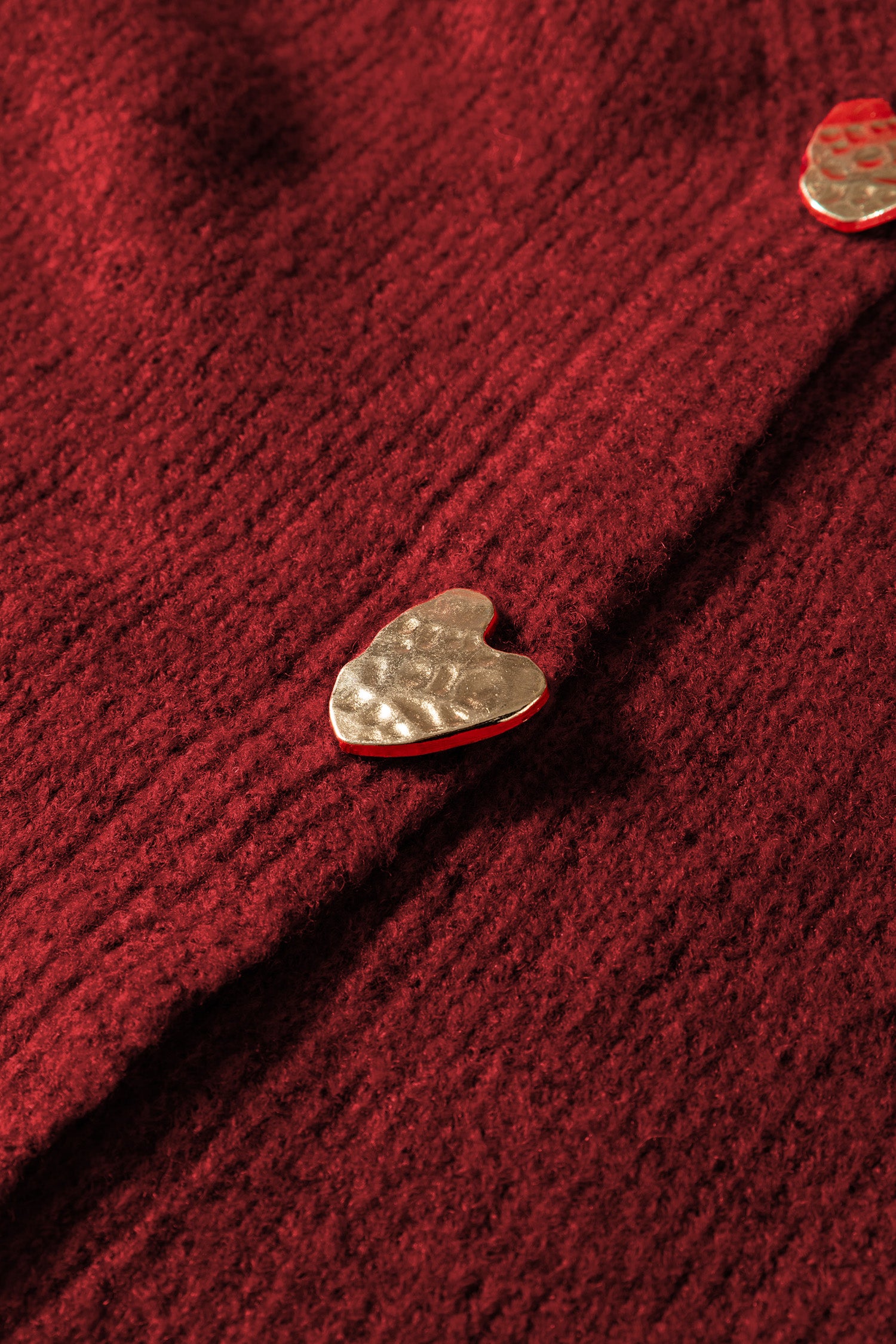 Детайл на V-образно деколте и копчета сърца на червена жилетка