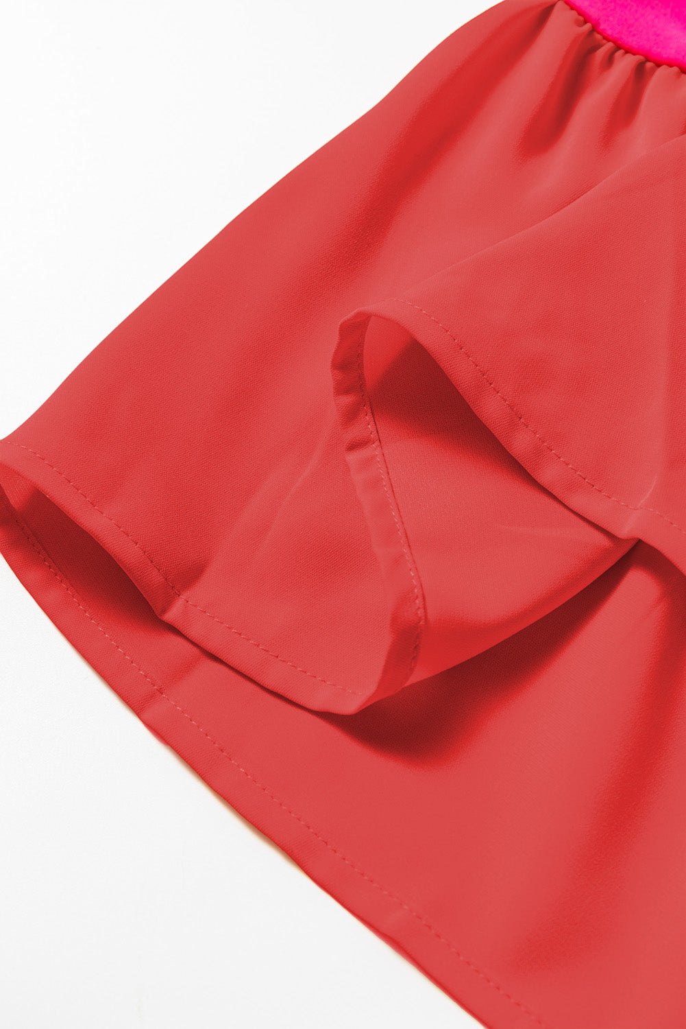 Close-up of red flowy skirt hem with visible stitching and lightweight fabric