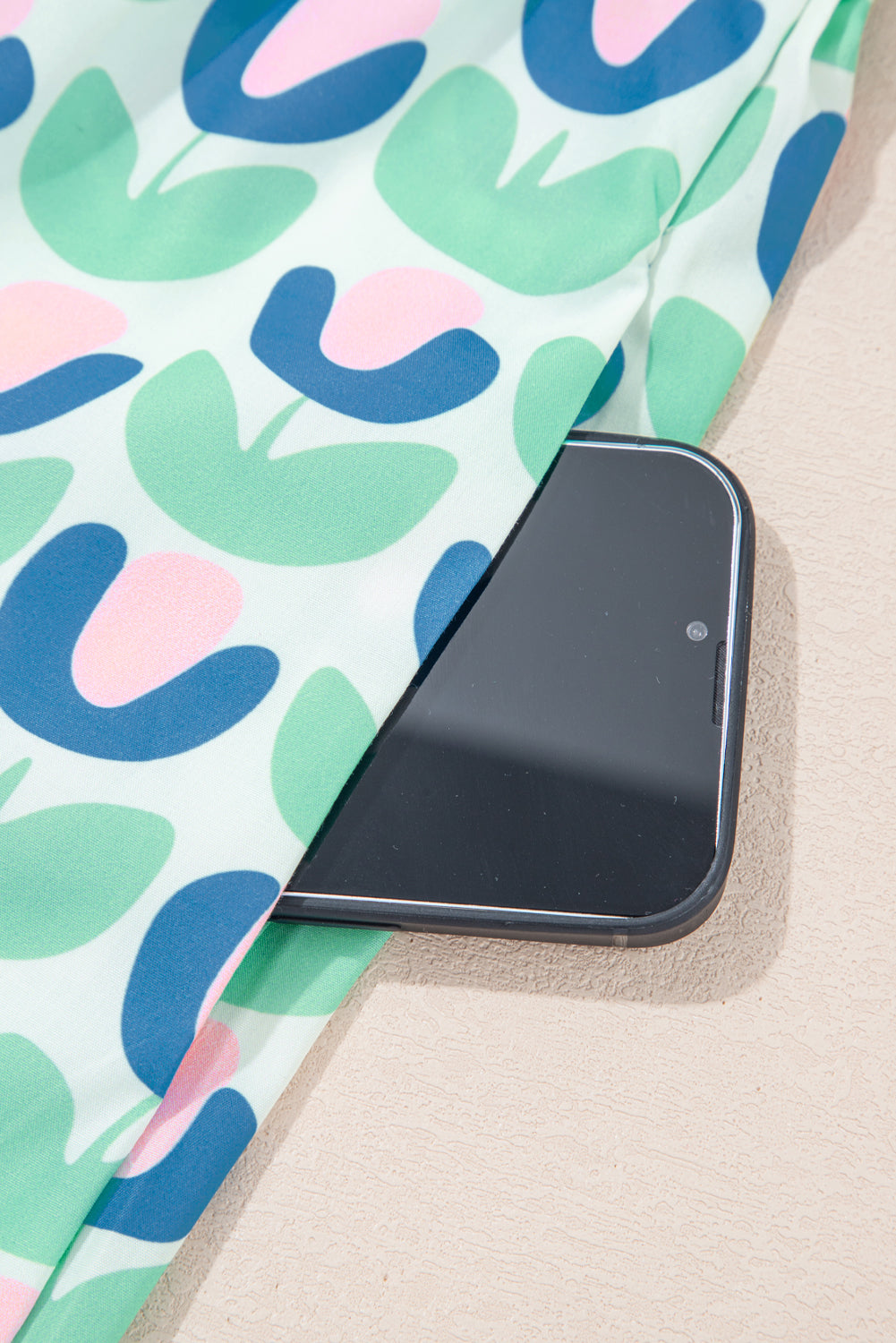 Smartphone in pocket of pastel floral print fabric, close-up, lifestyle fashion accessory
