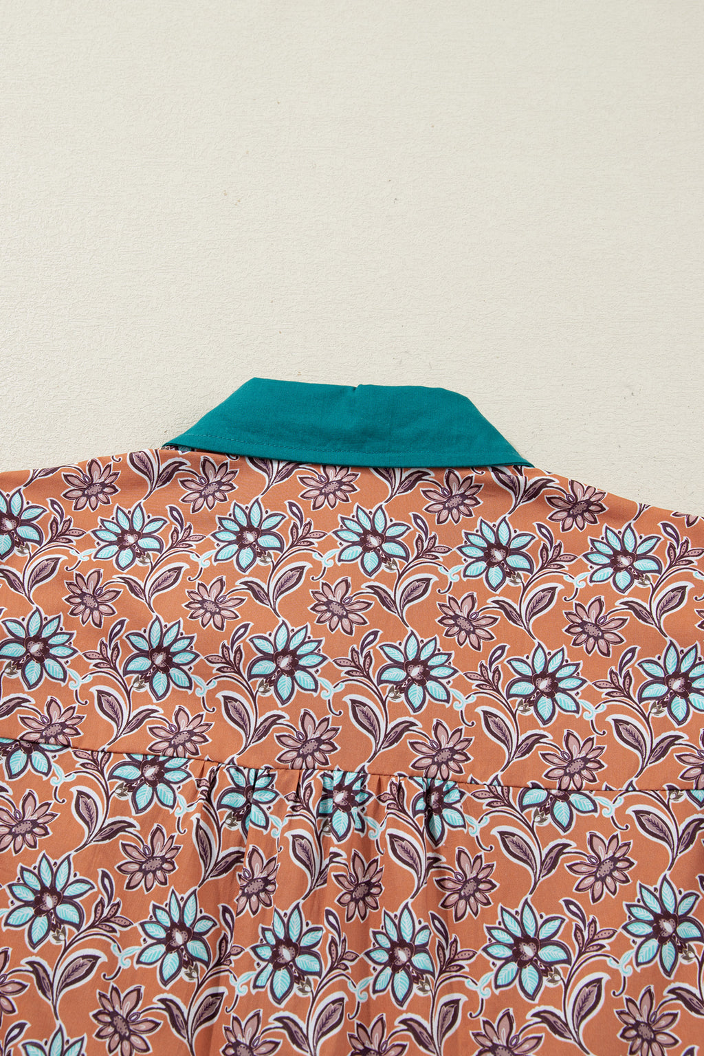 Shirt with teal collar and orange floral print pattern, close up of back neckline