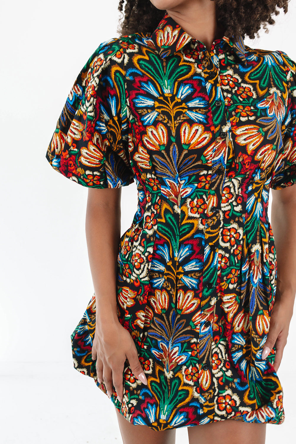 Woman wearing a short-sleeve button-up dress with bold colorful floral print