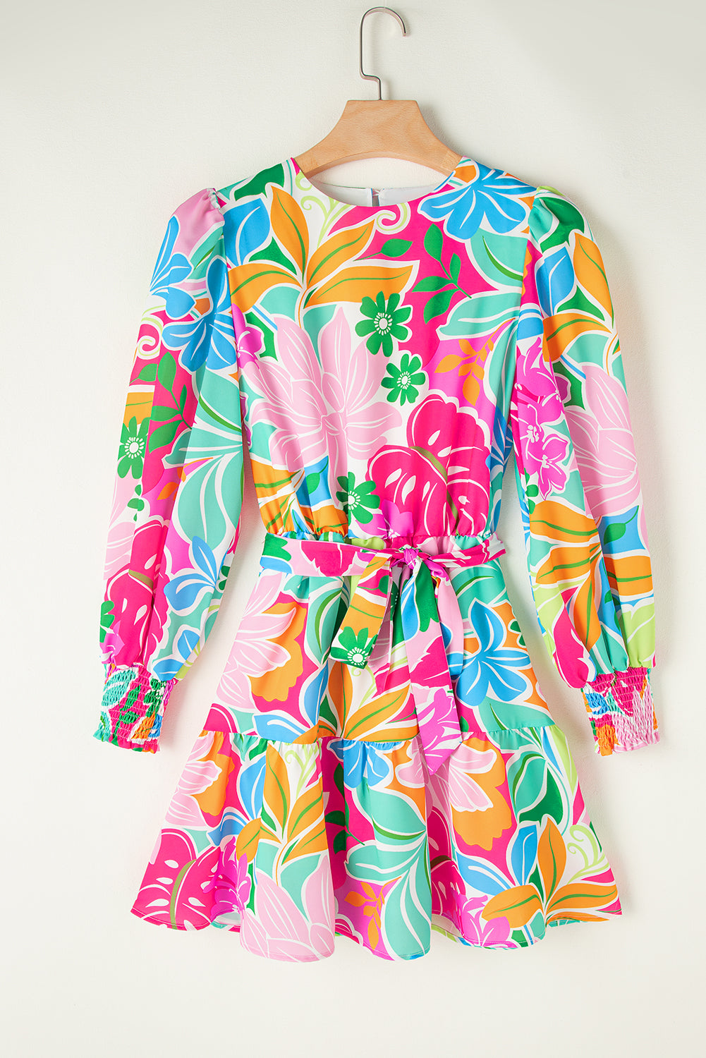 Colorful floral long-sleeve mini dress with tie waist and ruffle skirt, hanging on hanger