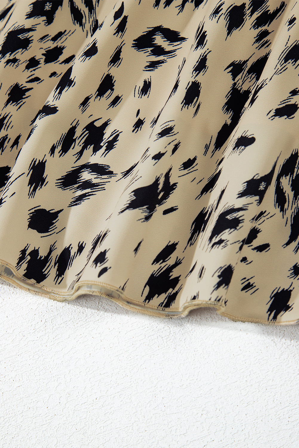 Beige skirt with black animal print pattern on textured white surface