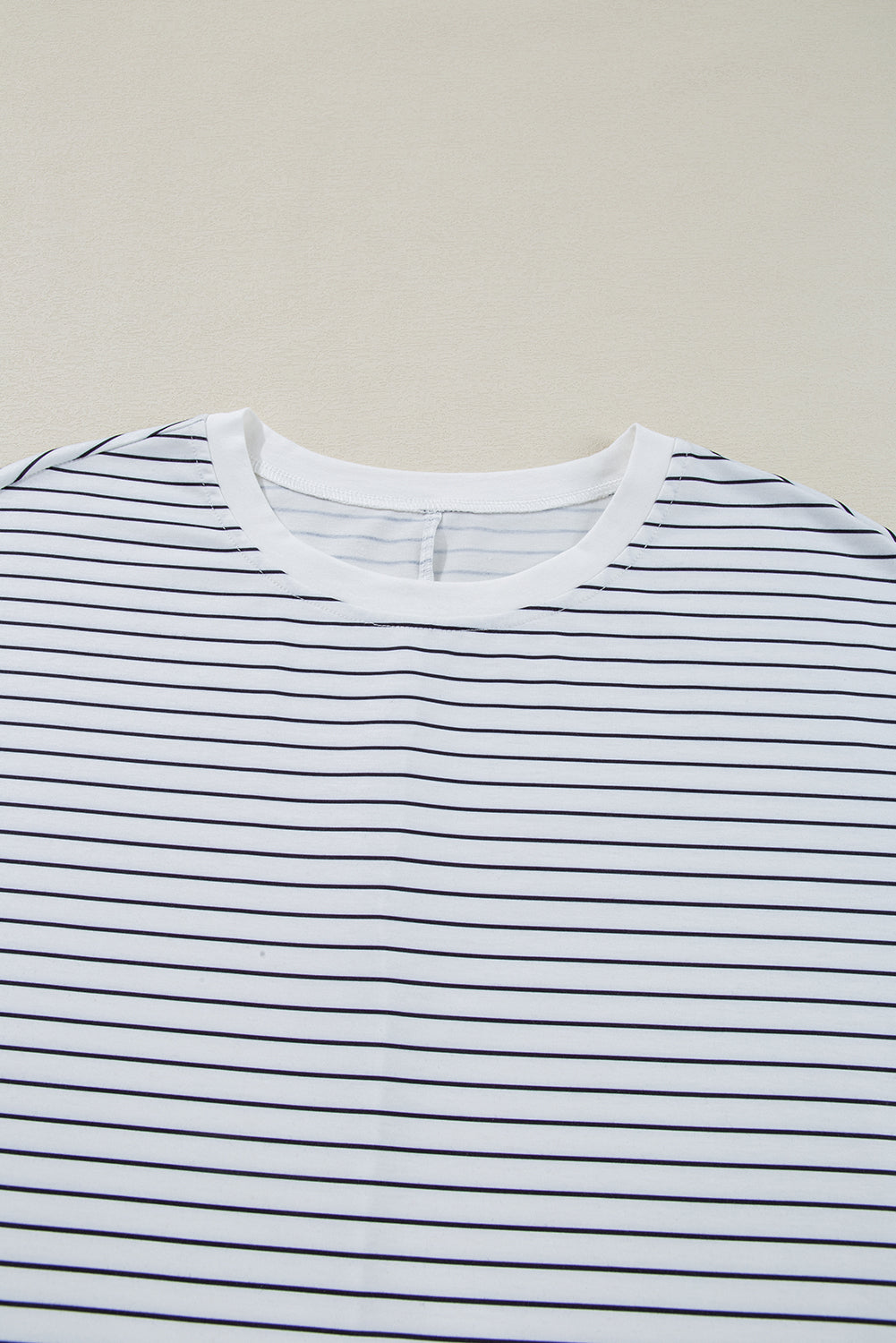 White crew neck t-shirt with thin black horizontal stripes on a light background