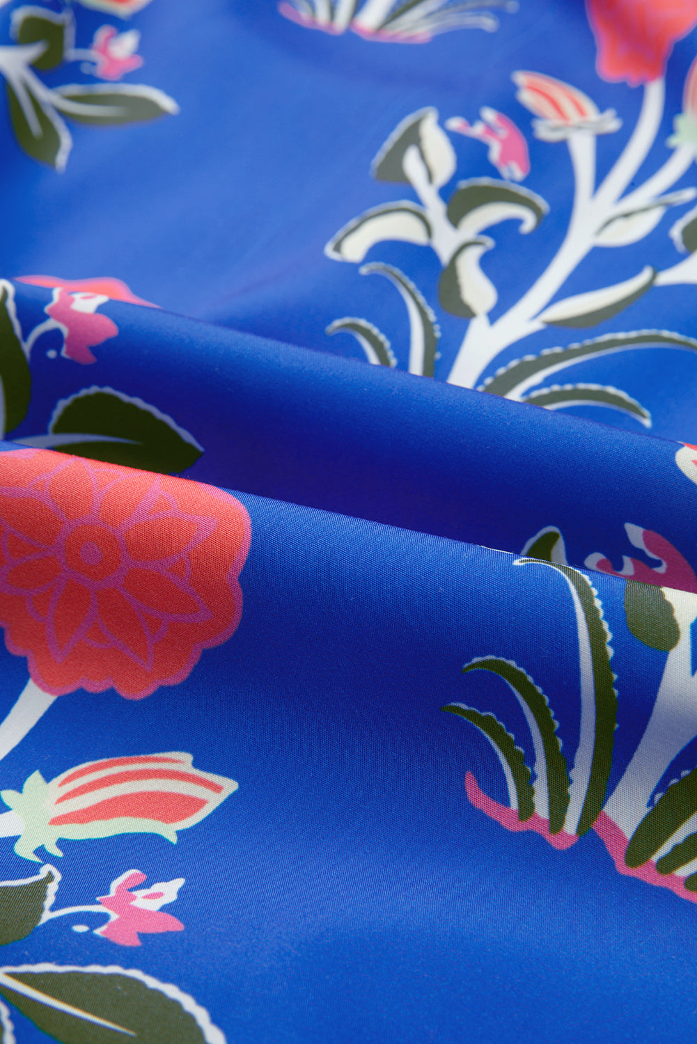 Blue floral fabric with pink and green flower print, close-up textile texture