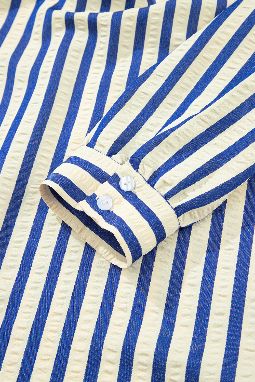 Blue and white striped shirt sleeve with buttoned cuff, textured fabric detail
