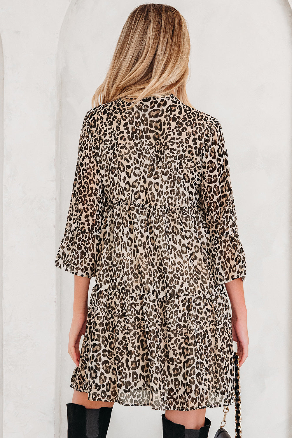 Woman wearing a leopard print dress with three-quarter sleeves and black knee boots
