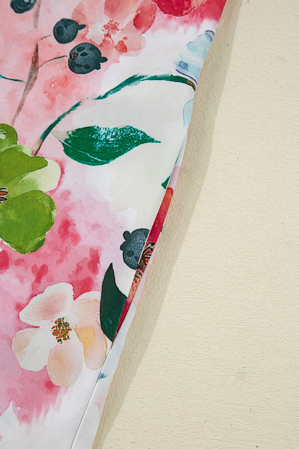 Close-up of floral print fabric in pink, green, and white colors on a light background