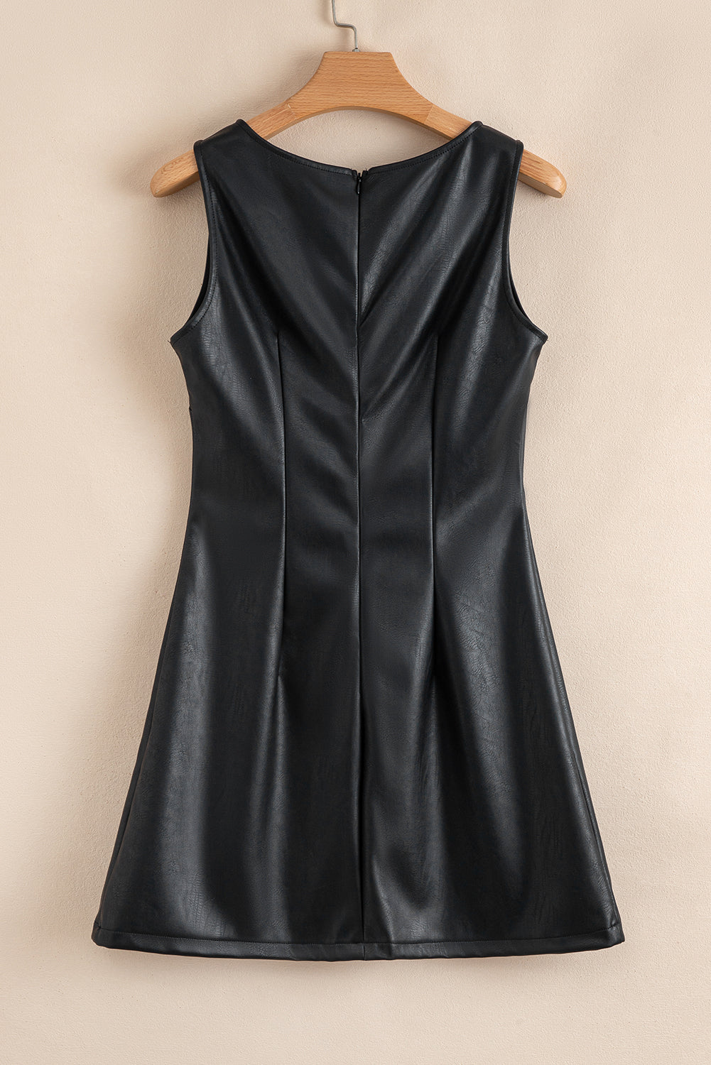 Sleeveless black faux leather dress with back zipper, displayed on wooden hanger