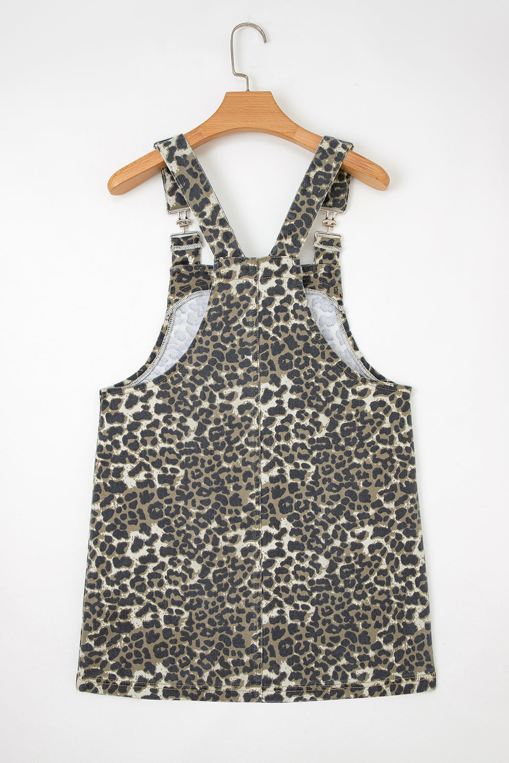 Leopard print overall dress with adjustable straps on wooden hanger