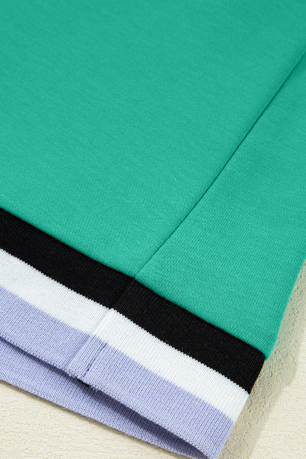 Green sweatshirt sleeve with black, white, and lavender ribbed cuff