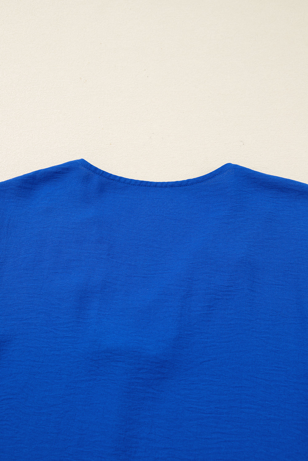 Close-up of a royal blue blouse back neckline on a light background