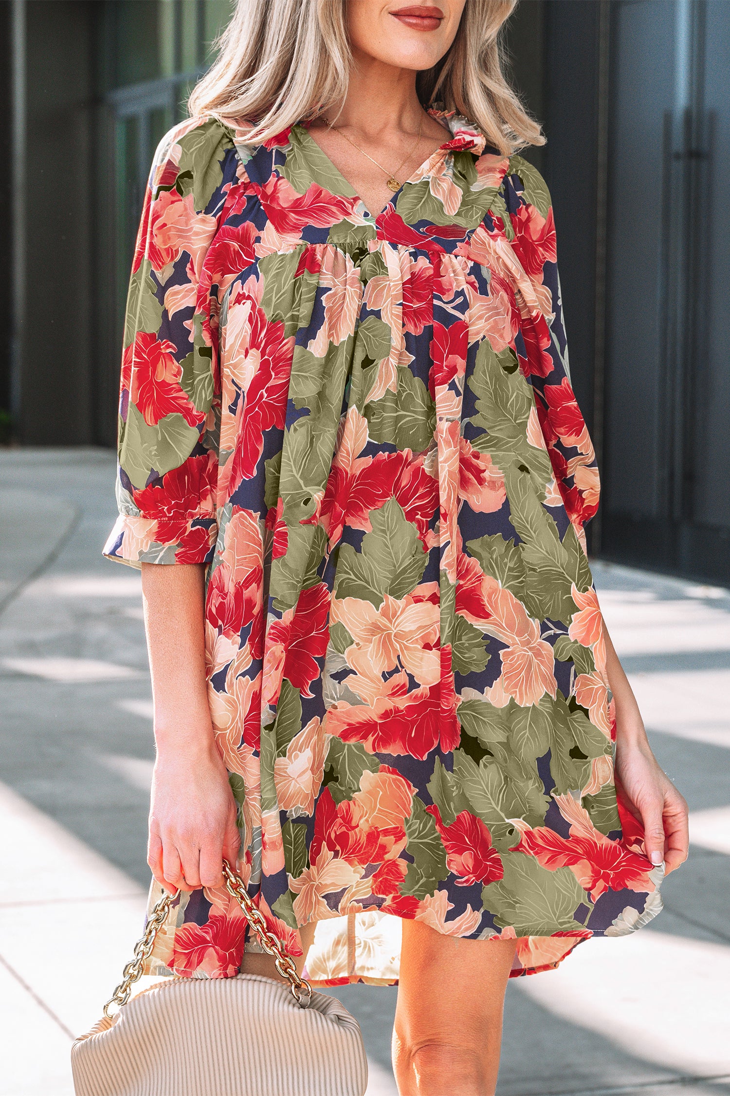 Woman wearing a loose floral dress with red, peach, and green leaf pattern outdoors