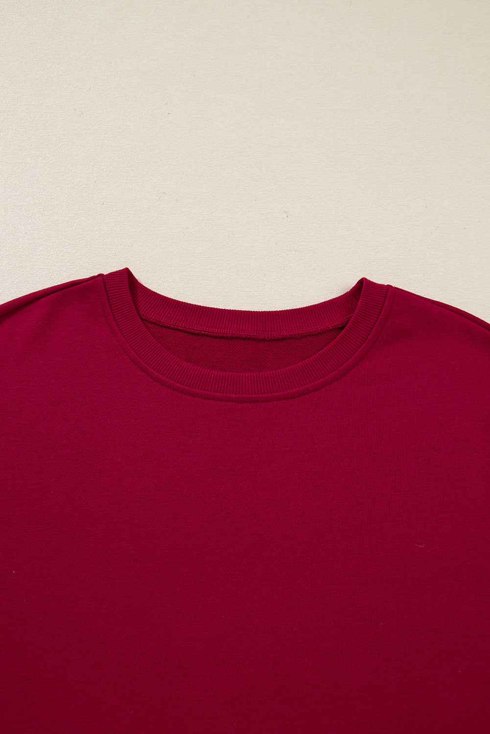 Close-up of a red crew neck t-shirt on a beige background