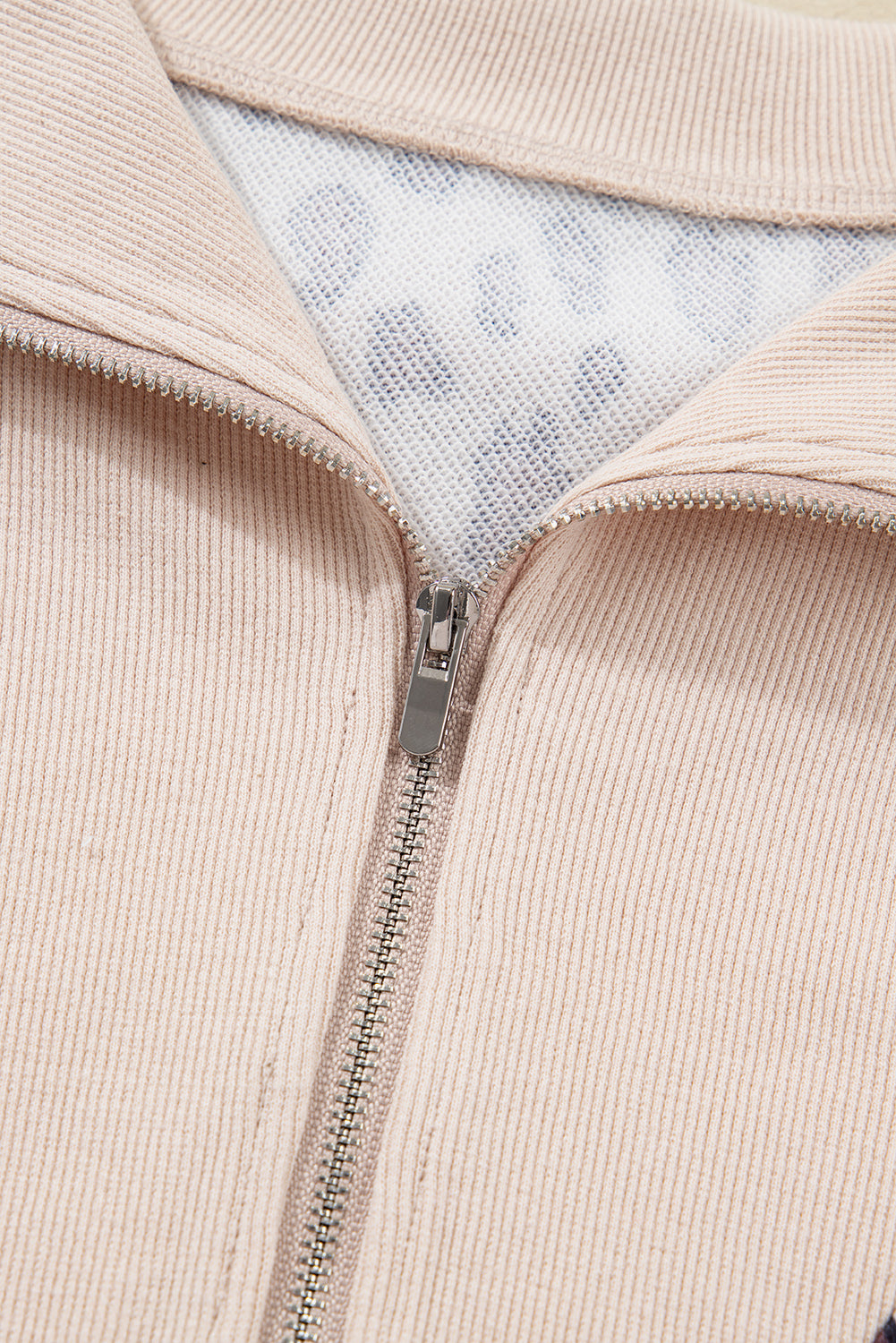 Close-up of beige ribbed zipper jacket with mesh and spotted inner lining