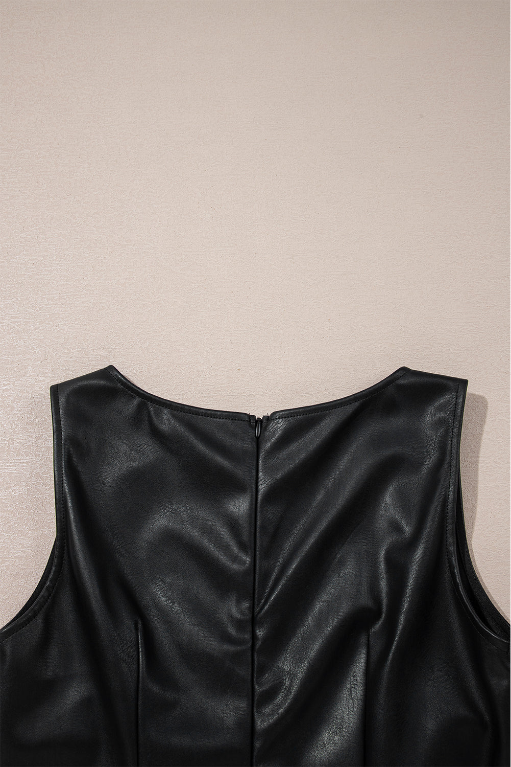 Black faux leather sleeveless dress with back zipper detail on neutral background