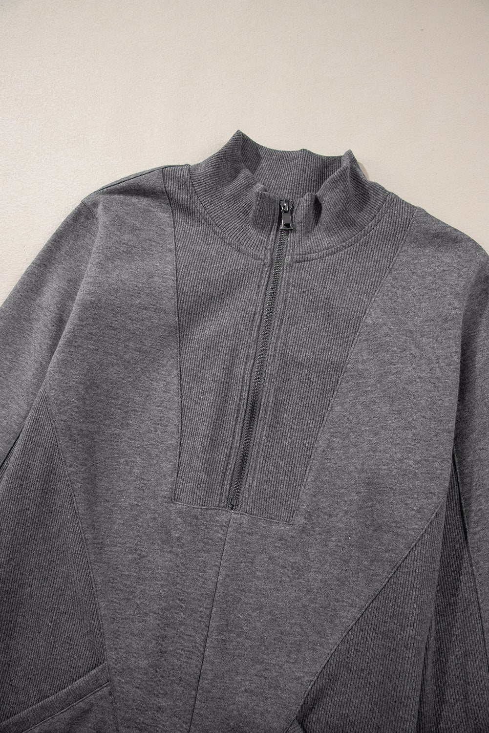Gray half-zip sweatshirt with ribbed panels and high collar, laid flat on a light background