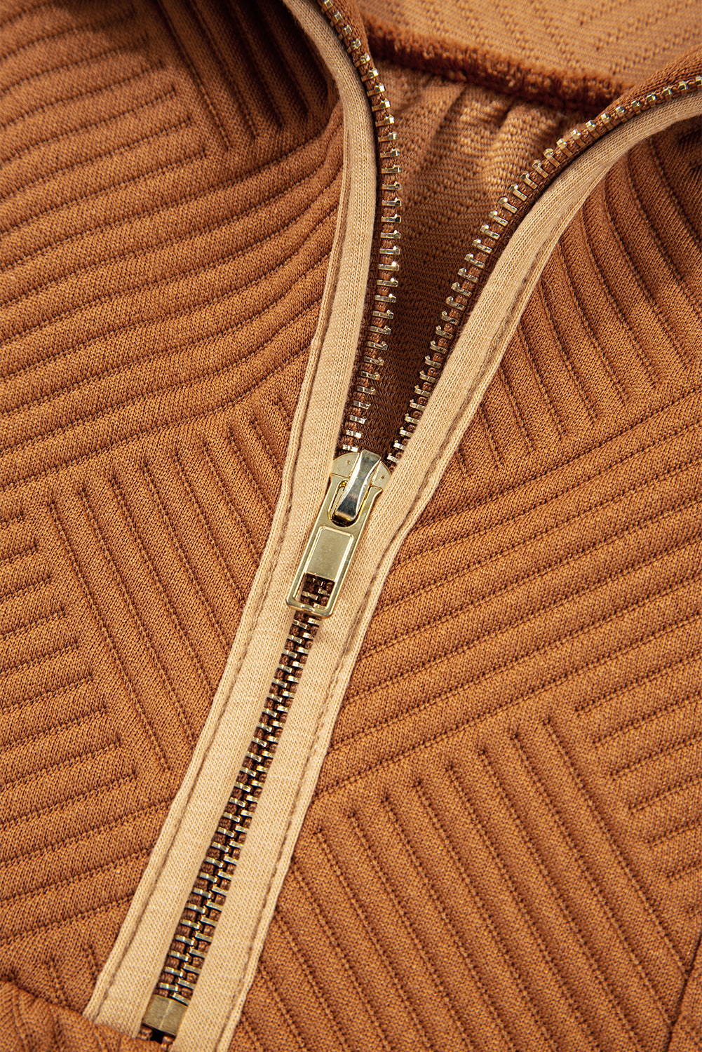 Close-up of brown ribbed knit fabric with a gold metal zipper