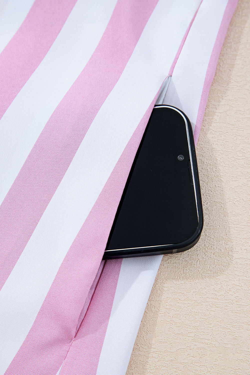 Smartphone in pocket of pink and white striped fabric garment, close-up