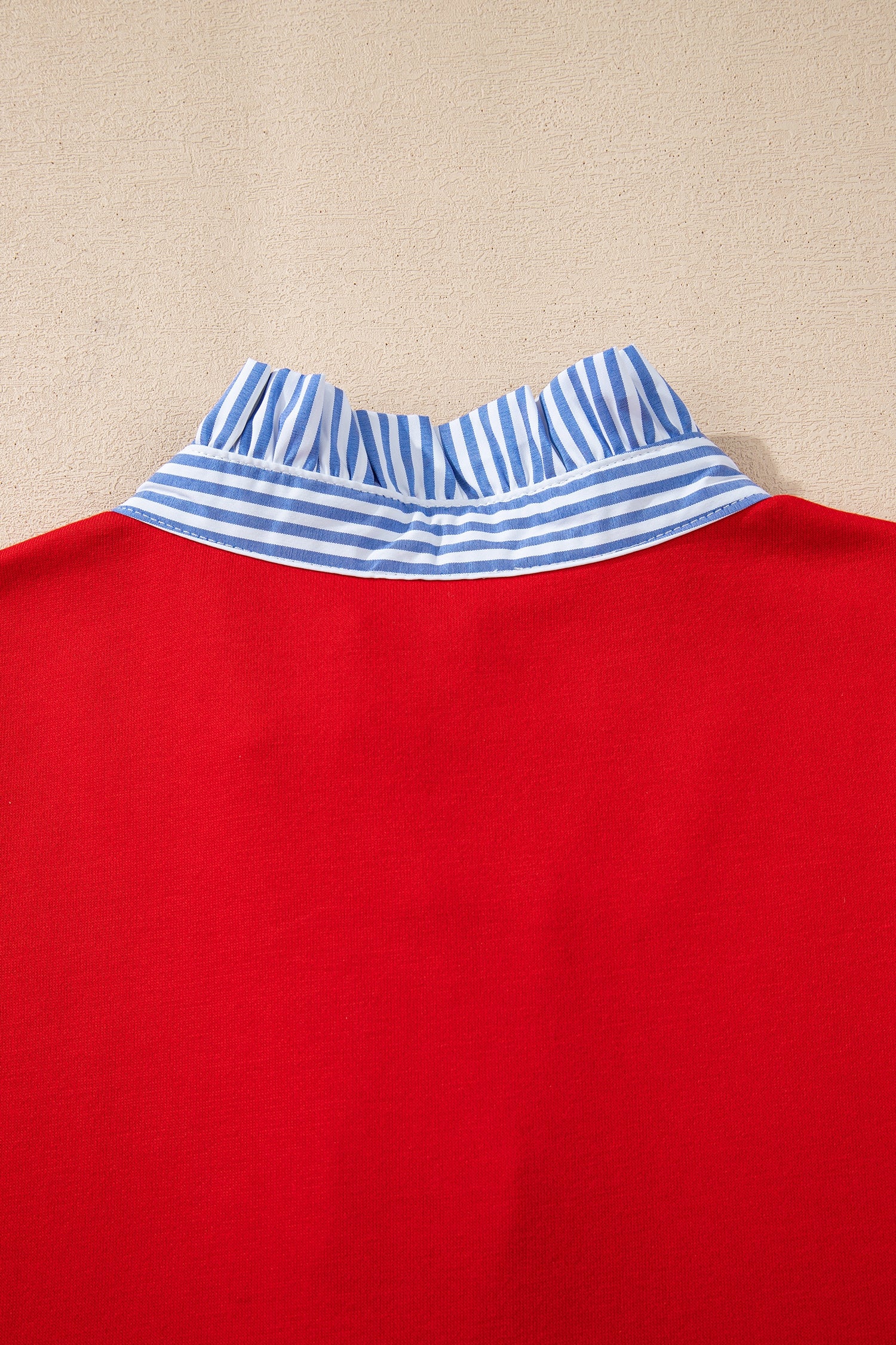Red top with blue and white striped ruffle collar detail, close-up back view