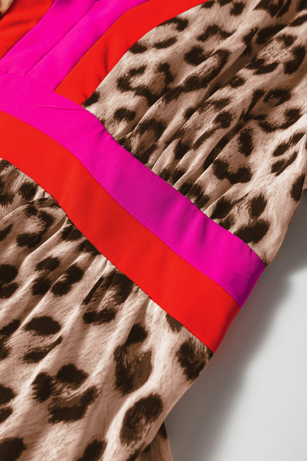 Leopard print fabric with bold red and pink color block stripes, close-up view