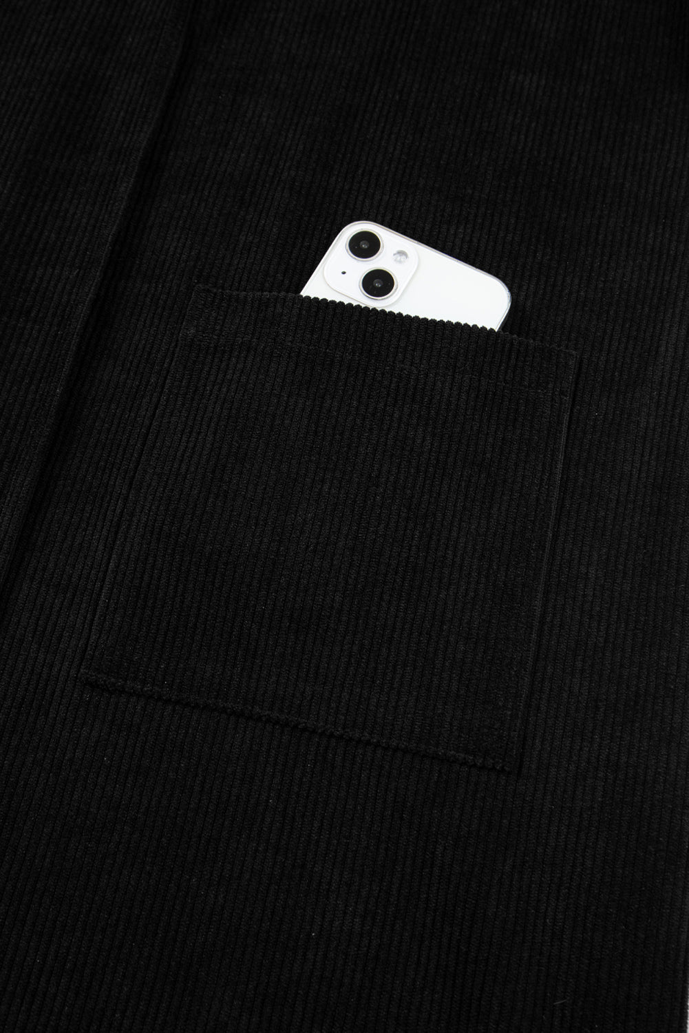 White smartphone in black corduroy jacket pocket, close-up texture detail