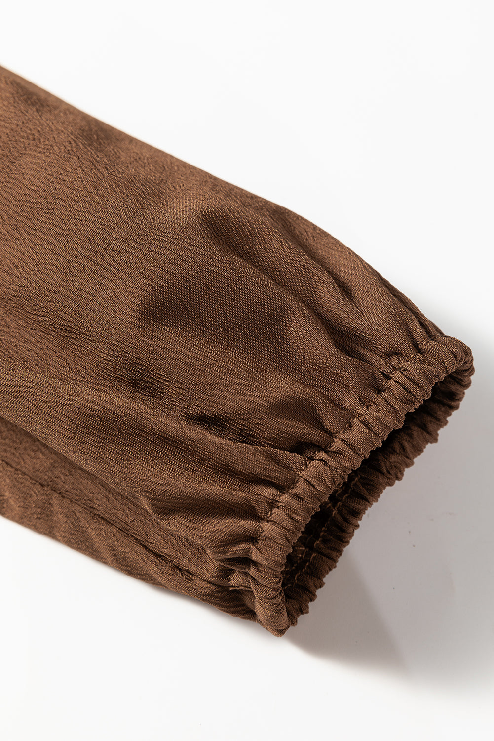 Close-up of brown textured fabric sleeve with elastic cuff for women's clothing