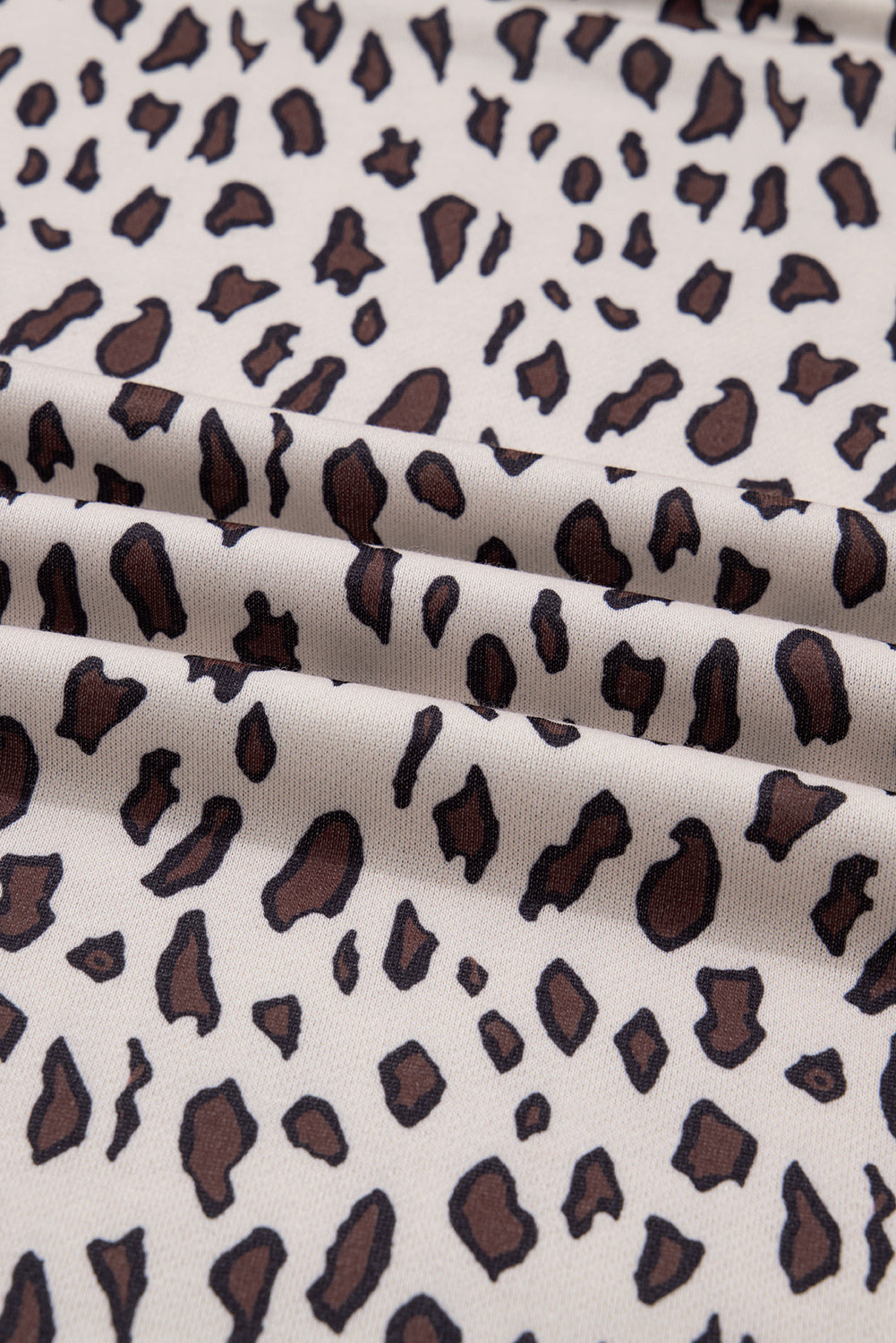 Beige fabric with brown and black leopard print pattern, close-up texture view