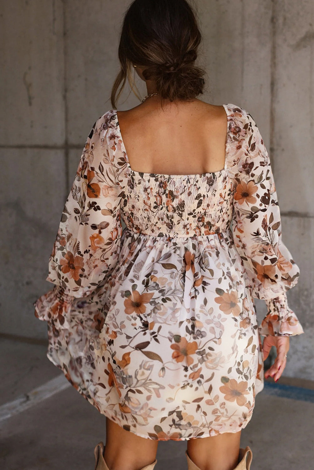 Woman in backless floral print mini dress with long sleeves, standing indoors