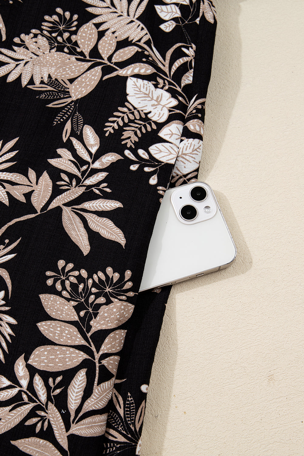 White smartphone in pocket of black floral print fabric pants