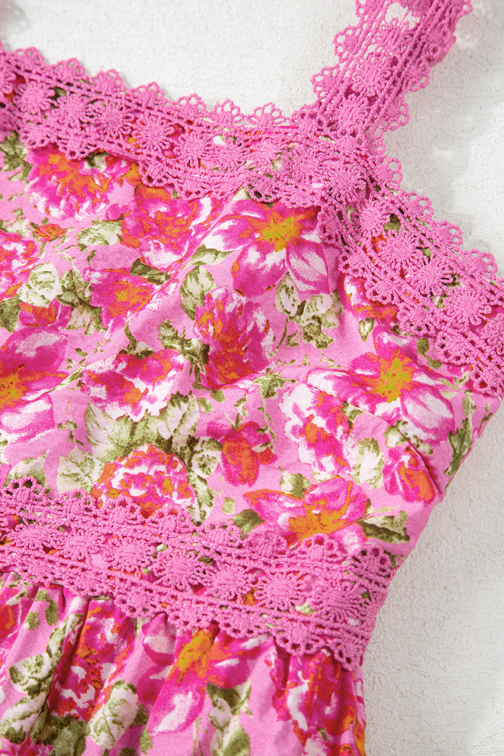 Pink floral dress with lace trim and spaghetti straps, vibrant flower print, close-up
