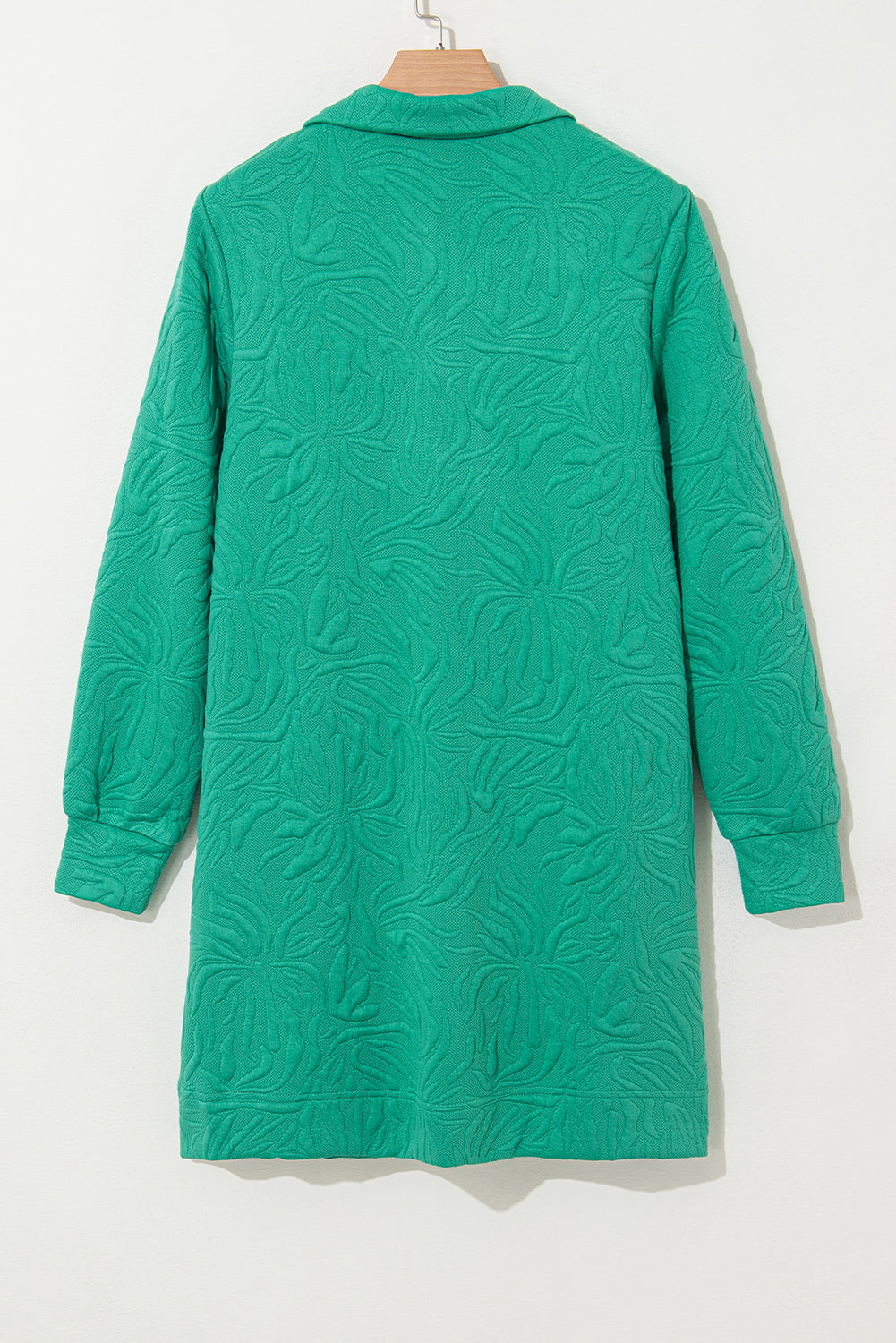 Green textured long-sleeve coat with floral pattern, hung on a wooden hanger