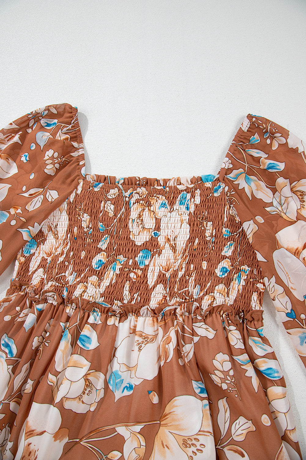 Brown floral print dress with smocked bodice and long puffed sleeves, flat lay