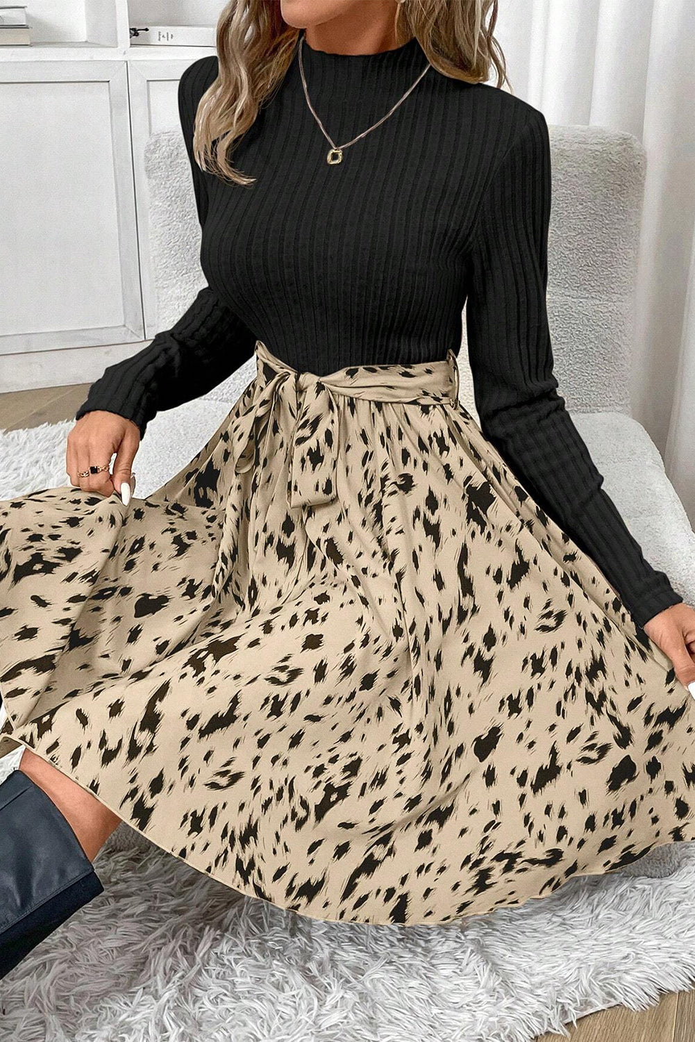 Woman wearing a black ribbed long sleeve top and beige animal print belted skirt