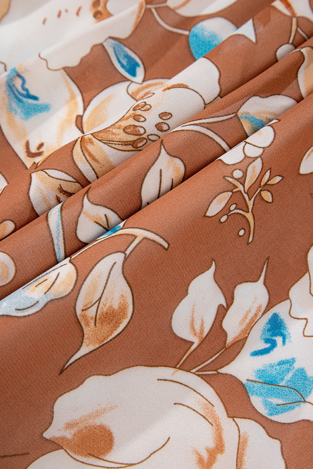 Brown and white fabric with floral pattern and blue accents, close-up texture