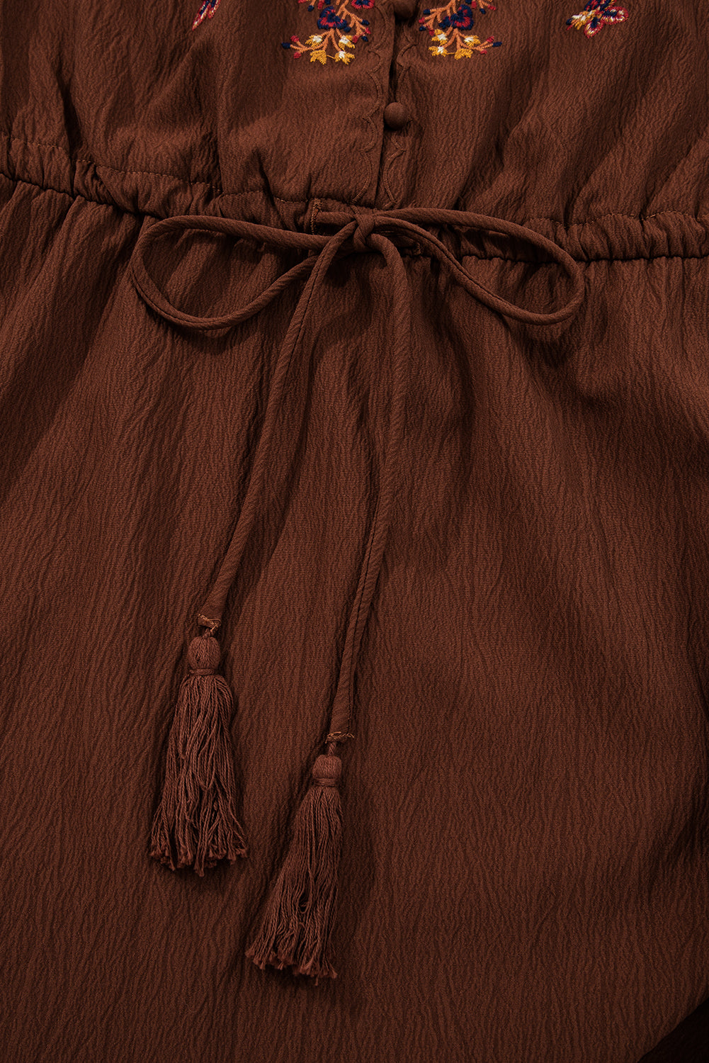 Brown textured dress with waist tie, tassels, and colorful floral embroidery detail