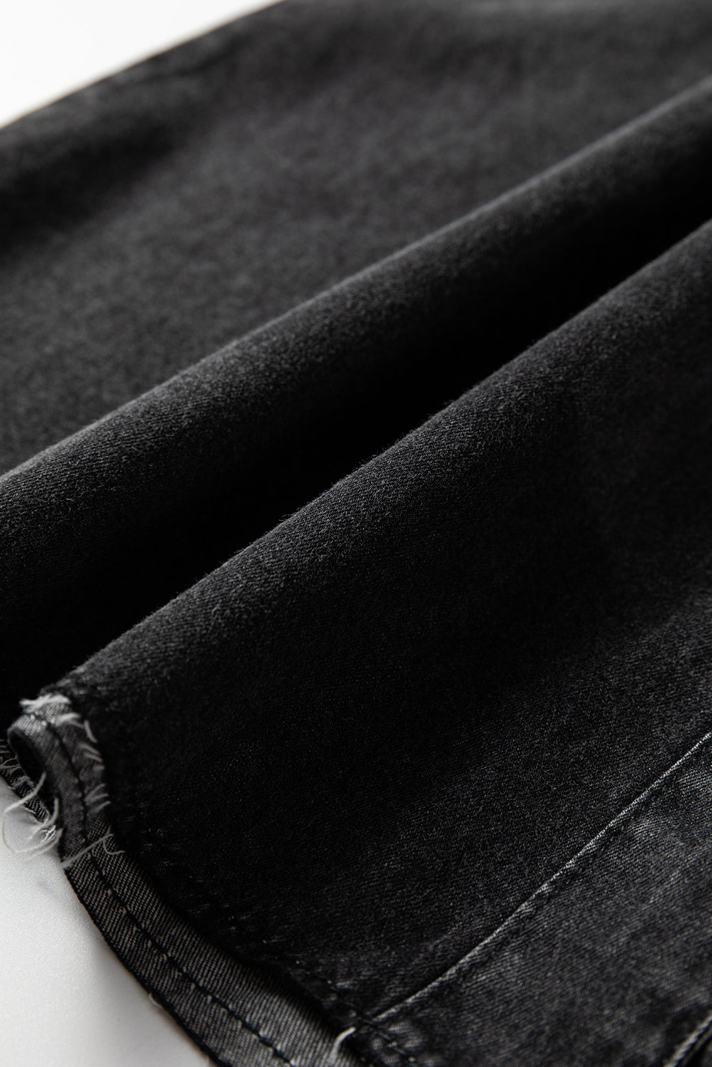 Close-up of soft black velvet fabric with finished seam detail, ideal for fashion apparel