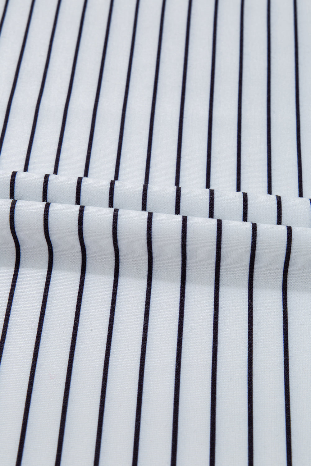White fabric with vertical black pinstripes, close-up textile detail