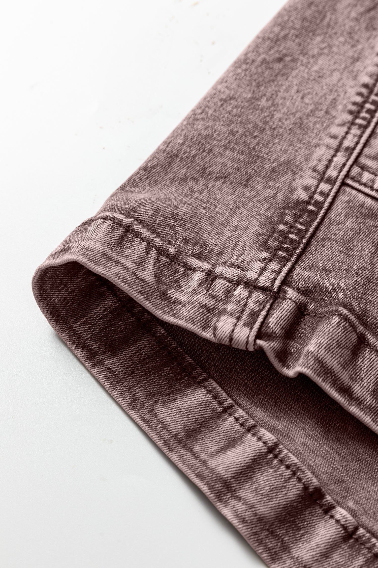 Close-up of hem on mauve denim jeans with visible stitching detail