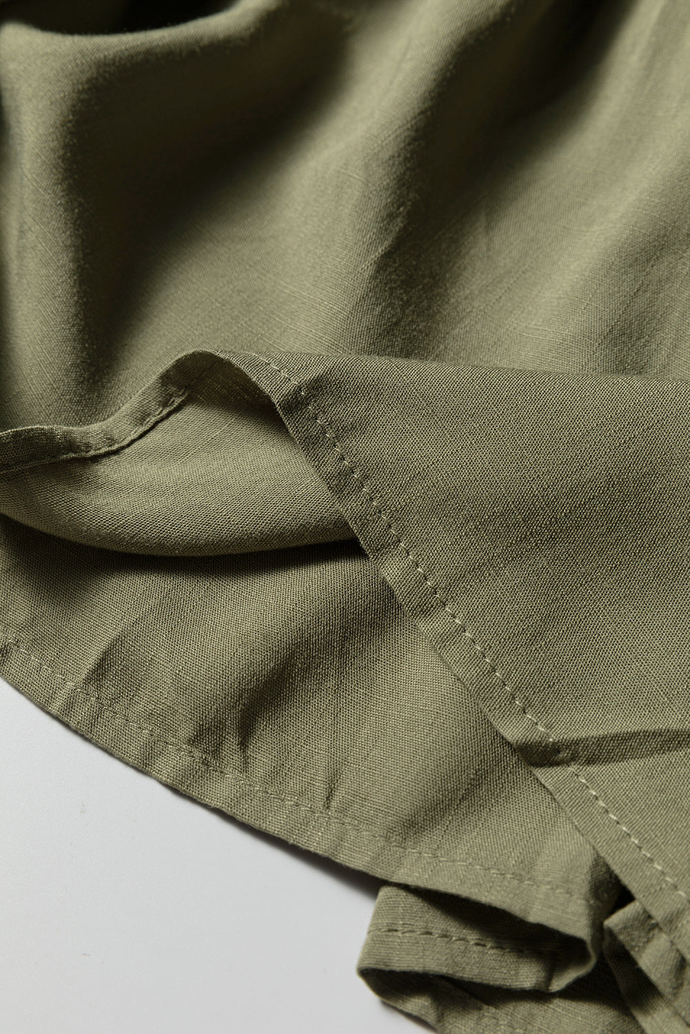 Close-up of olive green linen fabric with visible stitching, textile texture detail