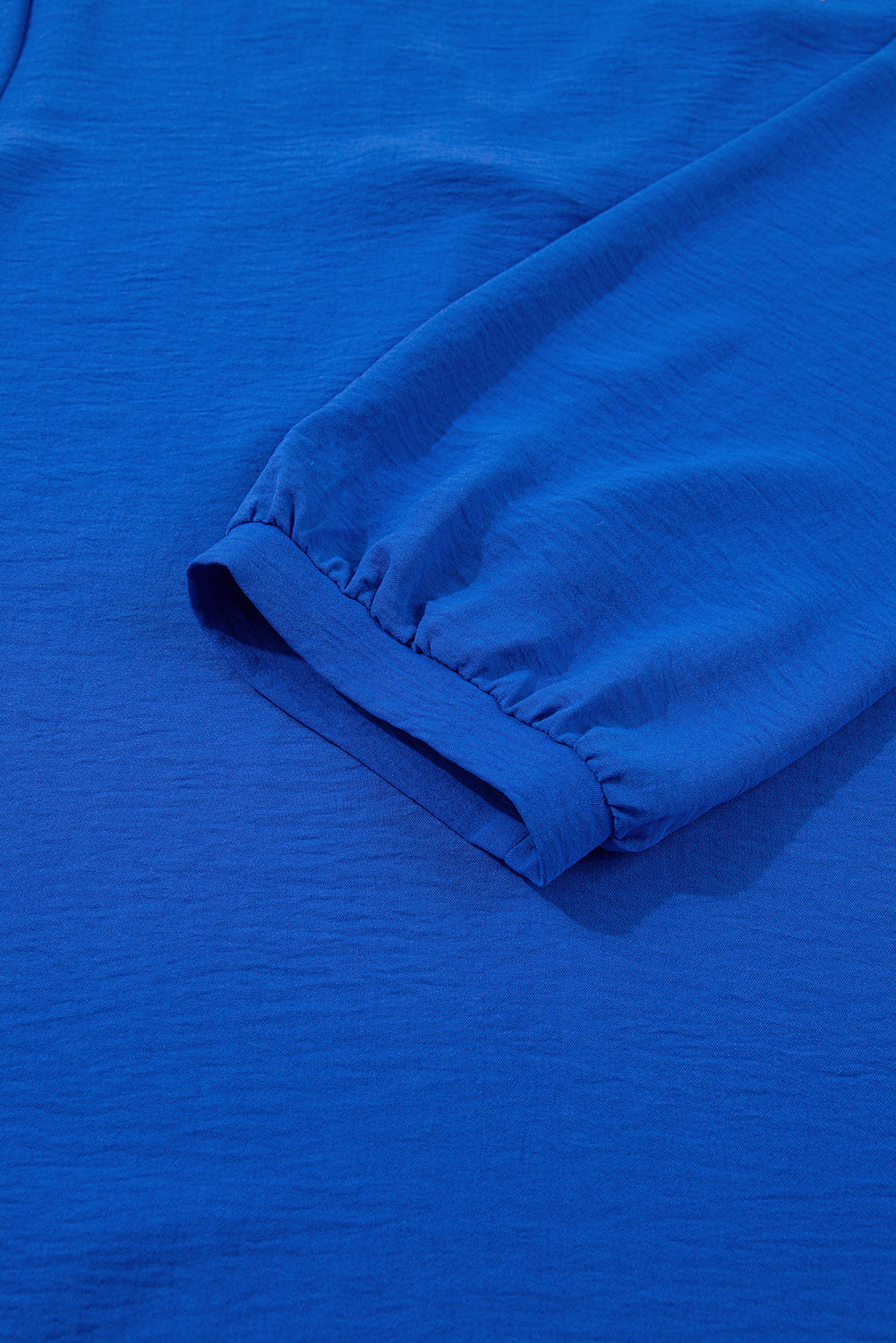 Bright blue long sleeve blouse with elastic cuff, textured fabric detail