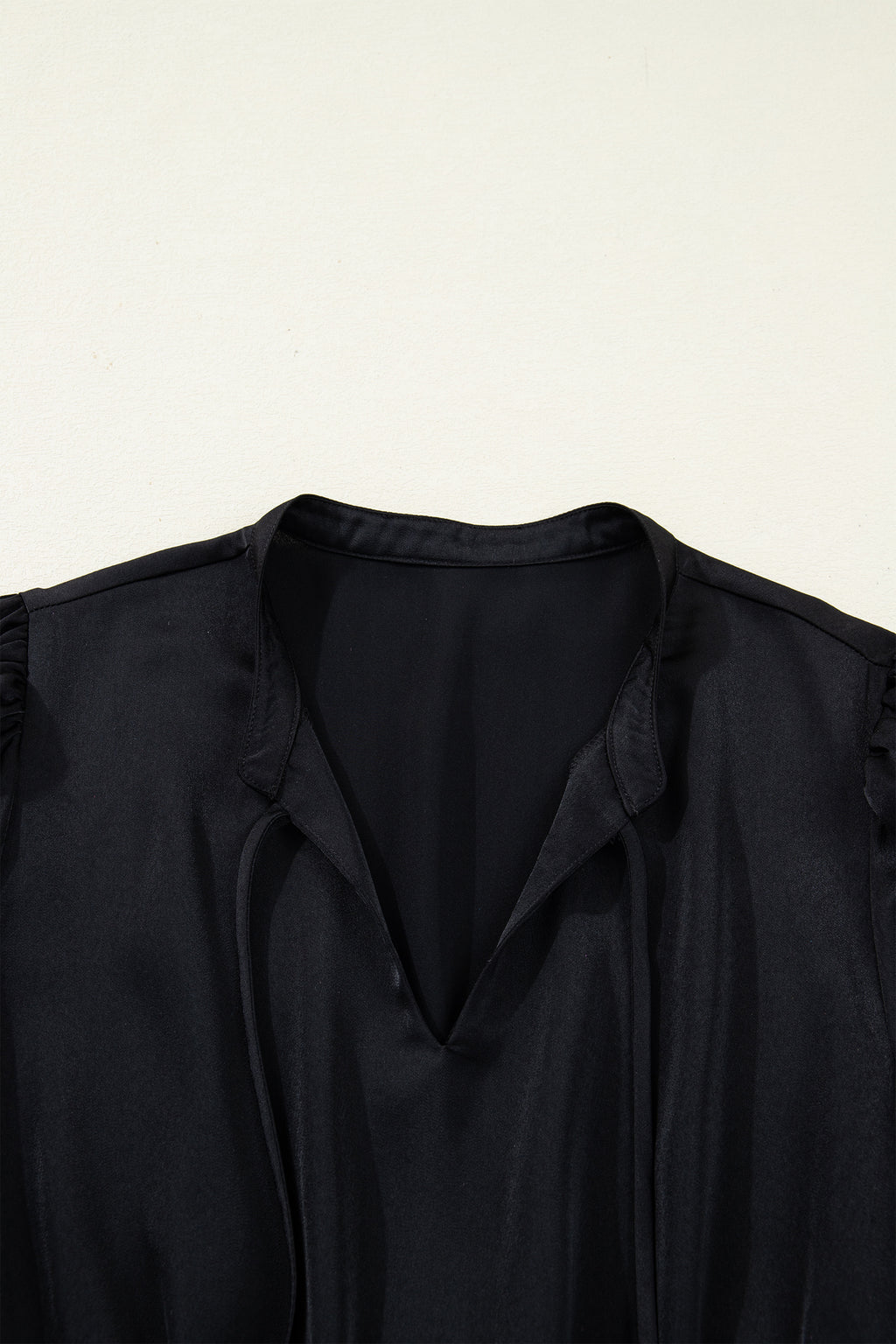 Close-up of black V-neck blouse with soft fabric and ruched shoulders