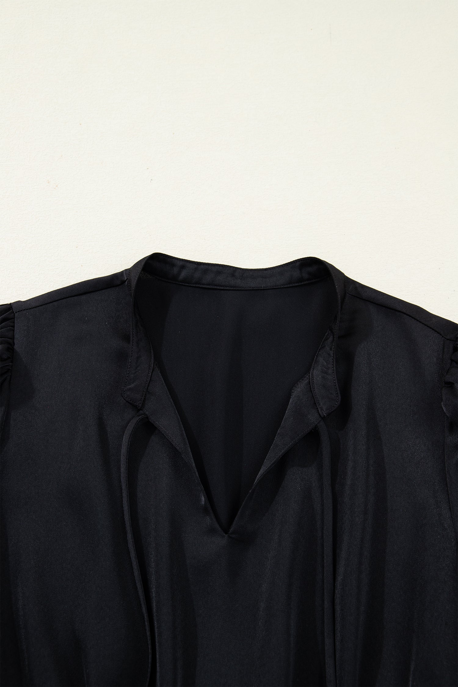 Close-up of black V-neck blouse with soft fabric and ruched shoulders