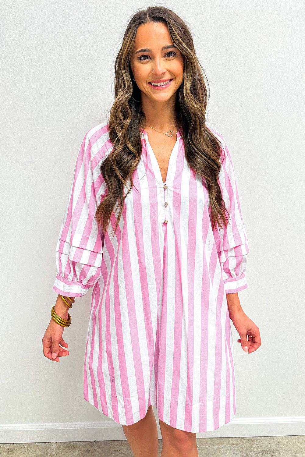 Woman wearing a pink and white vertical striped button-down dress with long sleeves