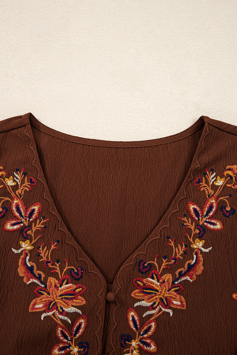 Brown V-neck blouse with colorful floral embroidery and scalloped edges
